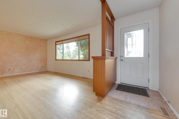 Entranceway with a white door and glass panel, wood partition, and light wood floor. - 15216 86 Av Nw, Edmonton