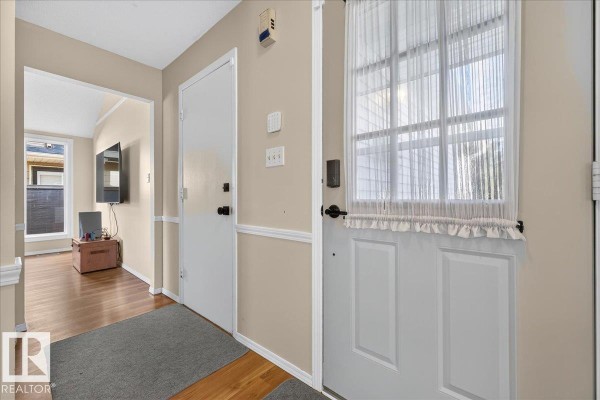 Interior entryway with light beige walls, white doors, and a gray rug on the floor. - 15228 84 St Nw, Edmonton