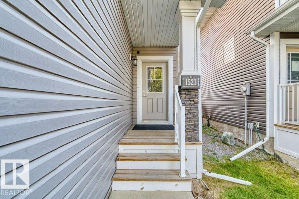 Front entrance porch with a glass-paneled door, stone column, and house number 1523. - 1523 168 St Sw, Edmonton