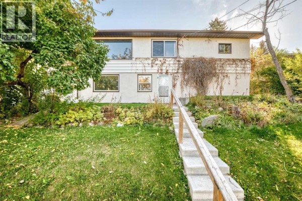 Front exterior of a beige house with large windows and a set of concrete stairs. - 1523 23 Street Nw, Calgary