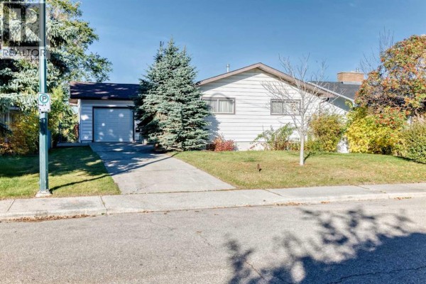 Front view of a white bungalow with a single-car garage and a paved driveway. - 1523 23 Street Nw, Calgary