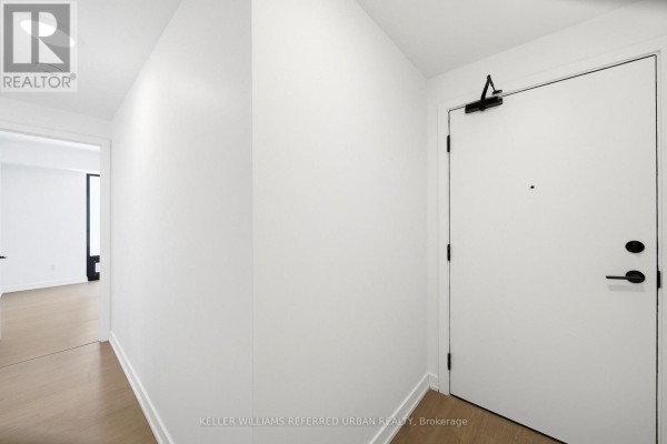 Interior hallway with white walls, hardwood floors, and a closed white entry door. - 1525 - 89 Montclair Avenue, Toronto