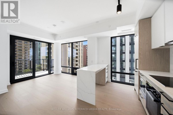 Open concept living area with kitchen island, floor-to-ceiling windows, and balcony access. - 1525 - 89 Montclair Avenue, Toronto