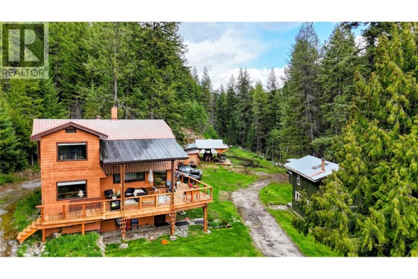 Aerial view of a wooden house and outbuildings nestled in a forested hillside. - 1525 Highway 3 / 95 Highway, Yahk