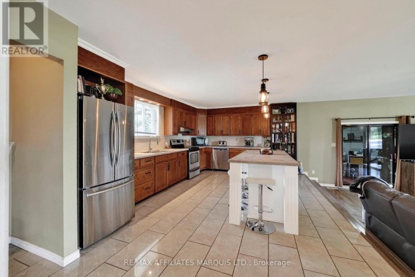 Kitchen with stainless steel refrigerator, wood cabinets, island, and pendant lights - 15253 County Road 2 Road South Stormont