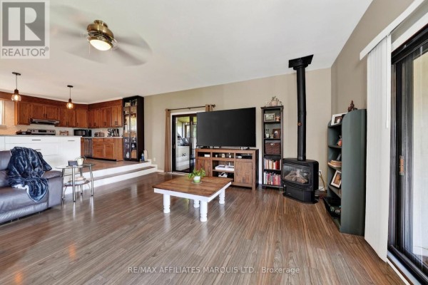 Living room with wood-burning stove, entertainment center, and open concept kitchen - 15253 County Road 2 Road South Stormont