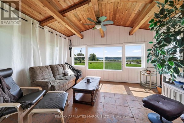 Sunroom with wood plank ceiling, sofa, armchairs, and water view - 15253 County Road 2 Road South Stormont