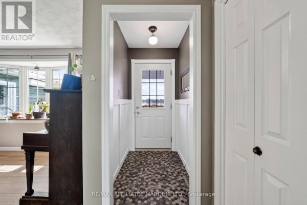 Hallway with paneled wainscoting, hexagonal tile floor, and glass door with water view - 15253 County Road 2 Road South Stormont