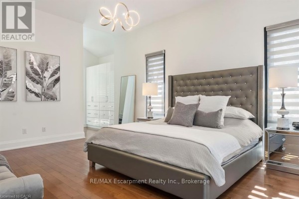 Bedroom with large window, striped blinds, and wooden furniture - 1526 Bridge Road Oakville