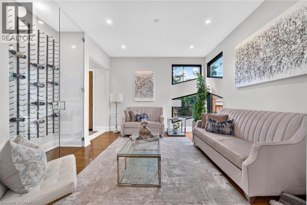 Dining area with glass table and upholstered chairs, next to a wooden staircase with glass railings. - 1526 Bridge Road, Oakville