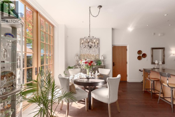 Dining area with table, chairs, chandelier, and a view of the kitchen island. - 1527 Atlas Lane, Vancouver