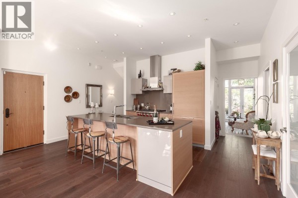 Open-concept kitchen with island, pendant lights, stainless steel appliances, and wooden flooring. - 1527 Atlas Lane, Vancouver