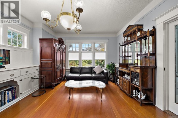 Living room with a black leather sofa, ornate furniture, and large windows. - 1528 Foul Bay Rd, Victoria