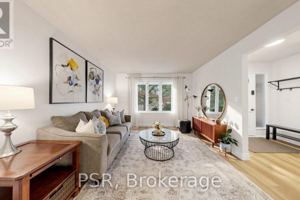 Living room with a sectional sofa, coffee table, large rug, and artwork on the wall. - 1528 Wildlark Drive, Peterborough