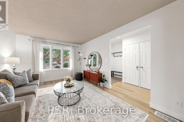 Living room with a sofa, coffee table, mirror, and view of a hallway with double doors. - 1528 Wildlark Drive, Peterborough
