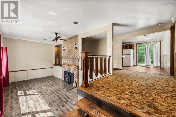 Living room with wood-look flooring, a brick fireplace, and an opening to a dining area. - 153 Argyle Head Road, Argyle Head