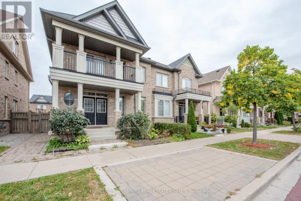 Exterior side view of a brick townhouse showing the entrance and balcony with a tree. - 153 Barons Street, Vaughan