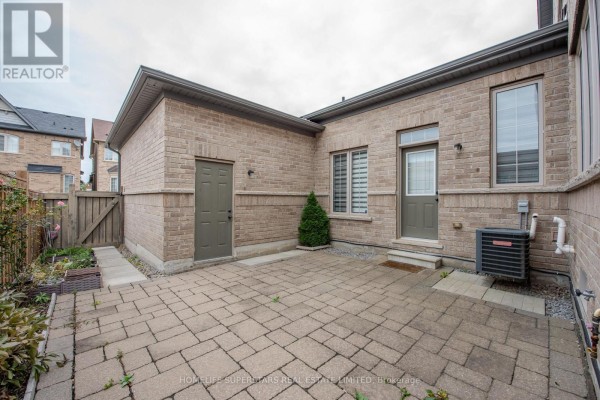 Rear brick exterior with a paved patio, a door, and an air conditioning unit. - 153 Barons Street, Vaughan