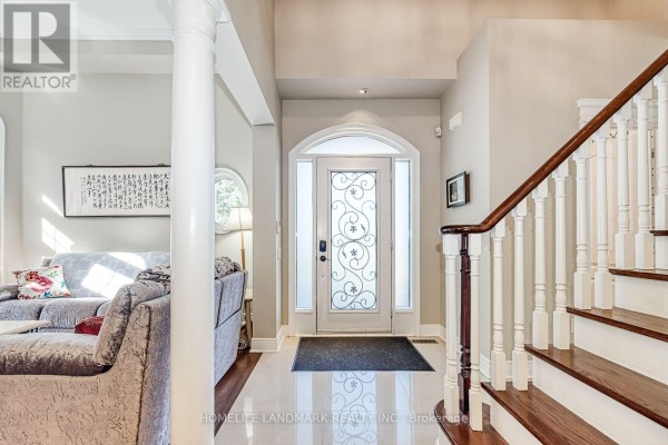 Foyer with a white staircase, hardwood floors, and a frosted glass door with decorative metal scrollwork. - 153 Britton Trail, Aurora
