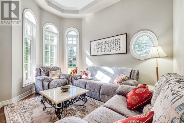 Living room with gray sectional sofa, plush armchairs, arched windows, and decorative wall art. - 153 Britton Trail, Aurora