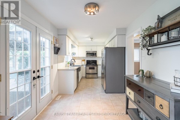 White kitchen with stainless steel appliances, light-colored countertops, and patio doors. - 153 Cardinal Street, Barrie