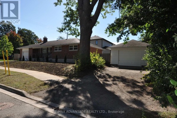 Side view of a red brick bungalow and detached garage with mature trees. - 153 Langarth Street W, London South