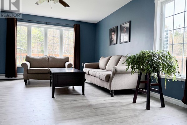 Living room featuring two sofas, a dark wood coffee table, and large windows with tree views. - 153 Main Street, Lourdes