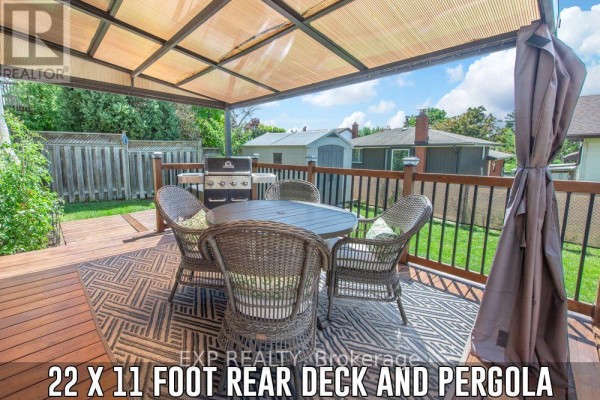 A covered wooden deck with a table, chairs, and gas grill. - 153 Oneida Place, Kitchener