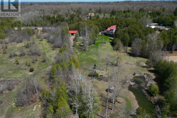 Aerial view of a rural property with a house, outbuilding, wooded areas, and fields. - 153 Pleasant Point Road, Kawartha Lakes