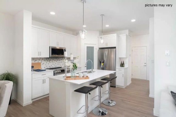 Open concept kitchen and living area with island, navy cabinets, and dining table. - 153 Rambling Road, Winnipeg