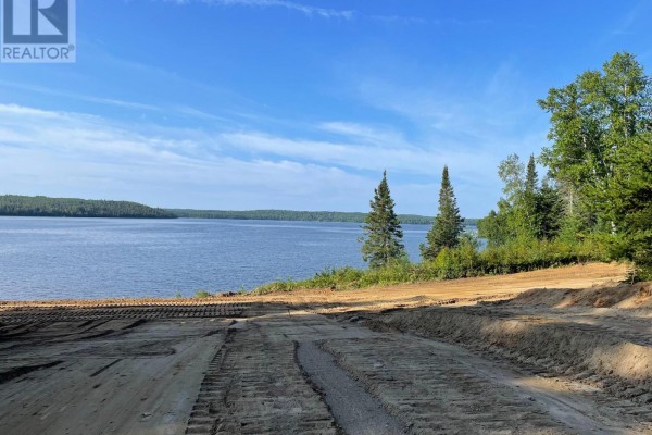 Waterfront property with cleared land and tire tracks, leading to a wide blue lake. - 153 Rudolph Road, Thunder Bay Remote Area