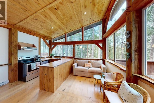 The open concept kitchen features wood counters, stainless steel appliances, and a sofa area. - 221 Sockeye Dr, Mudge Island