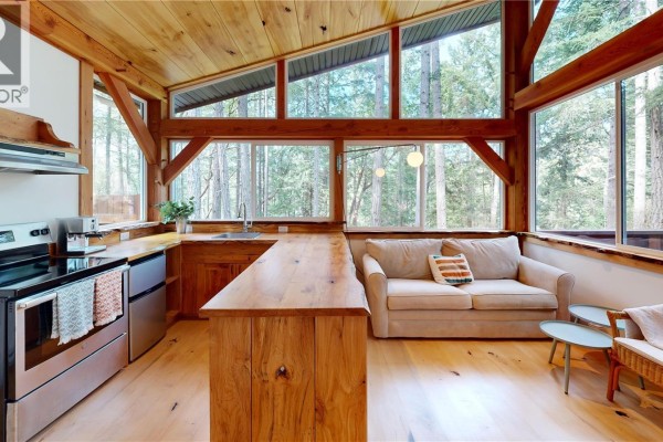 A light wood kitchen has a large island, stainless steel appliances, and a seating area. - 221 Sockeye Dr, Mudge Island
