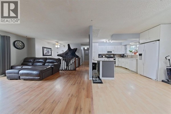 Open living area featuring a leather sectional and access to the kitchen - 1530 21 Highway, Creston