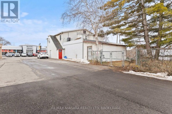 Side view of the building with a fenced area and parking lot in the background. - 1530 Niagara Stone Road, Niagara On The Lake