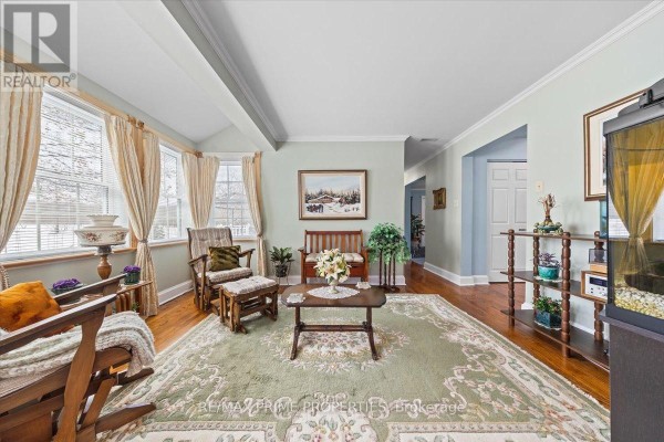 Living area with a bay window, wooden furniture, a large rug, and an aquarium. - 1530 Royal Orchard Drive, Ottawa