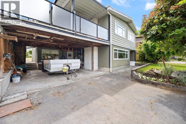 View of the covered carport area under the house, showing a trailer and storage items. - 1530 Sherlock Avenue, Burnaby