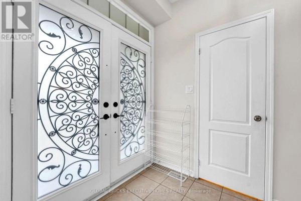 Interior view of a foyer with double glass doors, shoe rack, and a white door. - 1534 Scenic Lane Drive, Pickering