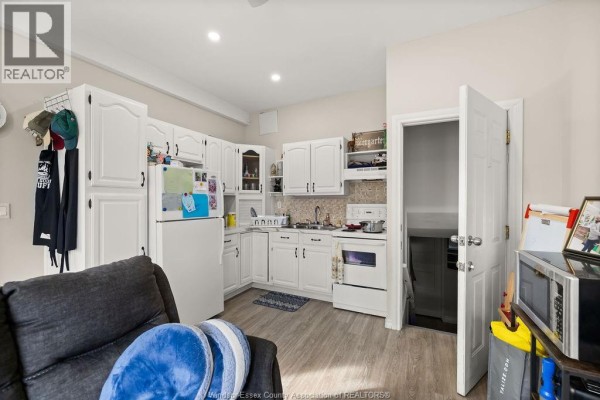 Kitchen with white cabinets, white refrigerator, white stove, and light grey laminate flooring. - 1537 Howard, Windsor