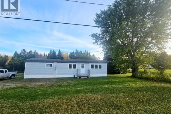 Side exterior of a light blue vinyl-sided single-wide mobile home with a large tree to the right. - 1539 Cormier, Robertville