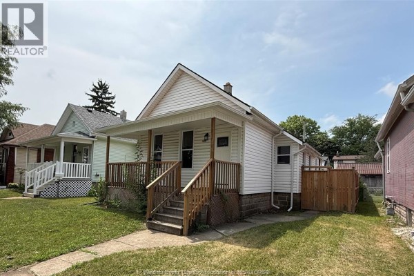 Side exterior of a white vinyl-sided house with a wooden porch and a wooden fence. - 1539 Windermere Road, Windsor