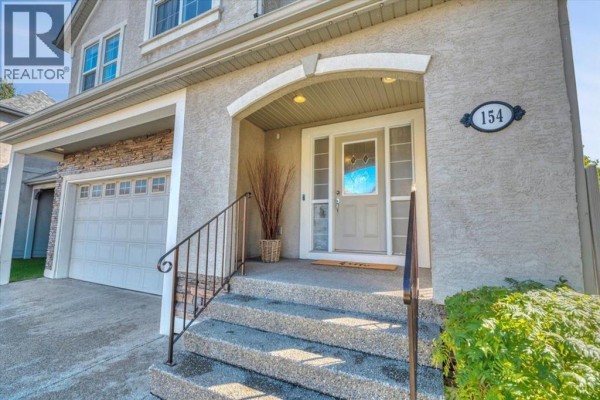Close-up of the front entrance with a covered porch, steps, and house number 154. - 154 Cranleigh Bay Se, Calgary