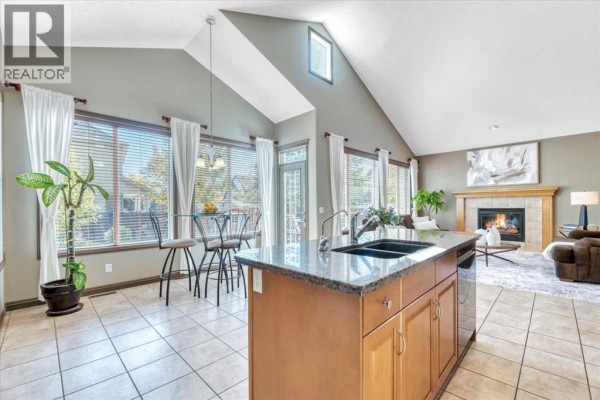 Kitchen island with a double sink, breakfast bar seating, and vaulted ceiling with skylight. - 154 Cranleigh Bay Se, Calgary