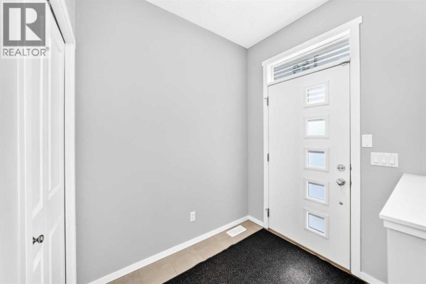 Interior view of a bright entryway with a white door and light grey walls. - 154 Livingston Avenue Ne, Calgary