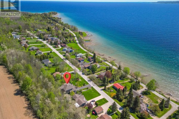 Aerial view of a residential street with houses, trees, and a large blue body of water. - 154 Macintosh Drive, Georgian Bluffs