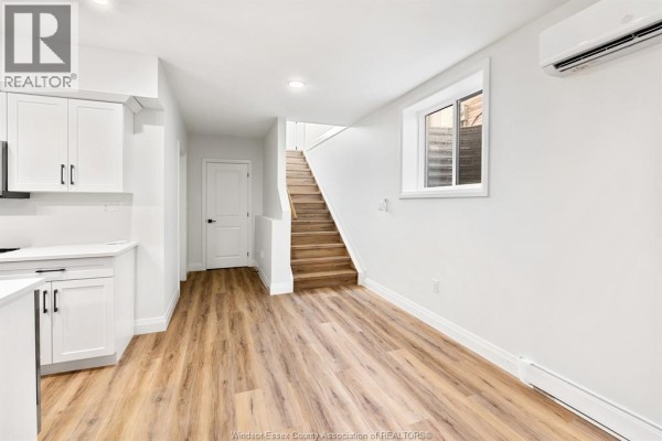 A small kitchen with white cabinets, quartz countertops, and a short staircase. - 154 Mclellan Avenue Unit# B (lower), Amherstburg