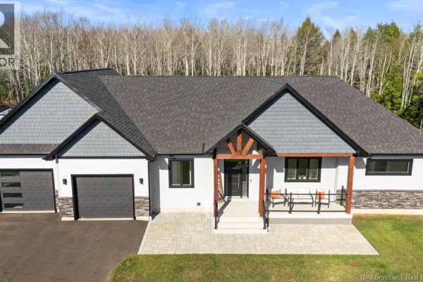 Close-up front view of the house entrance with a covered porch, gray siding, stone accents, and double garage doors. - 154 Pit Melanson Cross Road, Saint Antoine