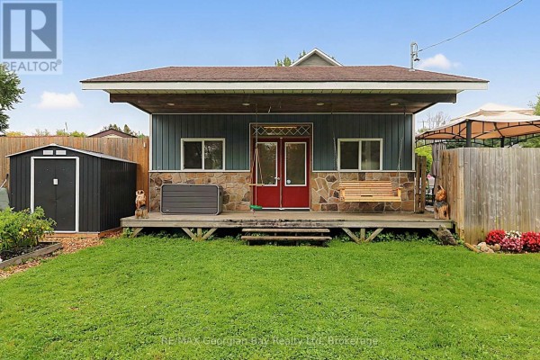 Covered front porch with swing, red doors, shed, and hot tub enclosure - 154 Robert Street W Penetanguishene