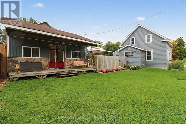 Exterior with wooden porch, swing, red doors, and stone facade - 154 Robert Street W Penetanguishene
