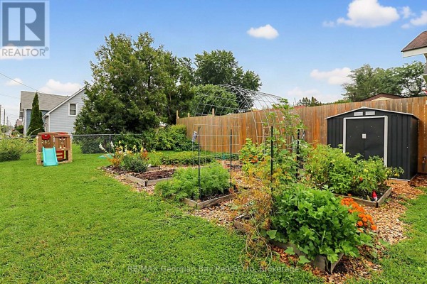 Raised garden beds, shed, play structure, and greenhouse frame in backyard - 154 Robert Street W Penetanguishene